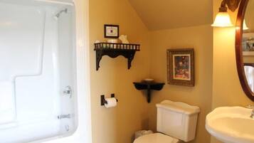 Ein Badezimmer mit Toilette, Waschbecken, Dusche und einem gerahmten Bild an der Wand.