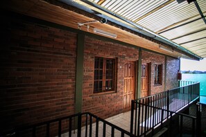 A brick building with a wooden balcony and a metal roof.