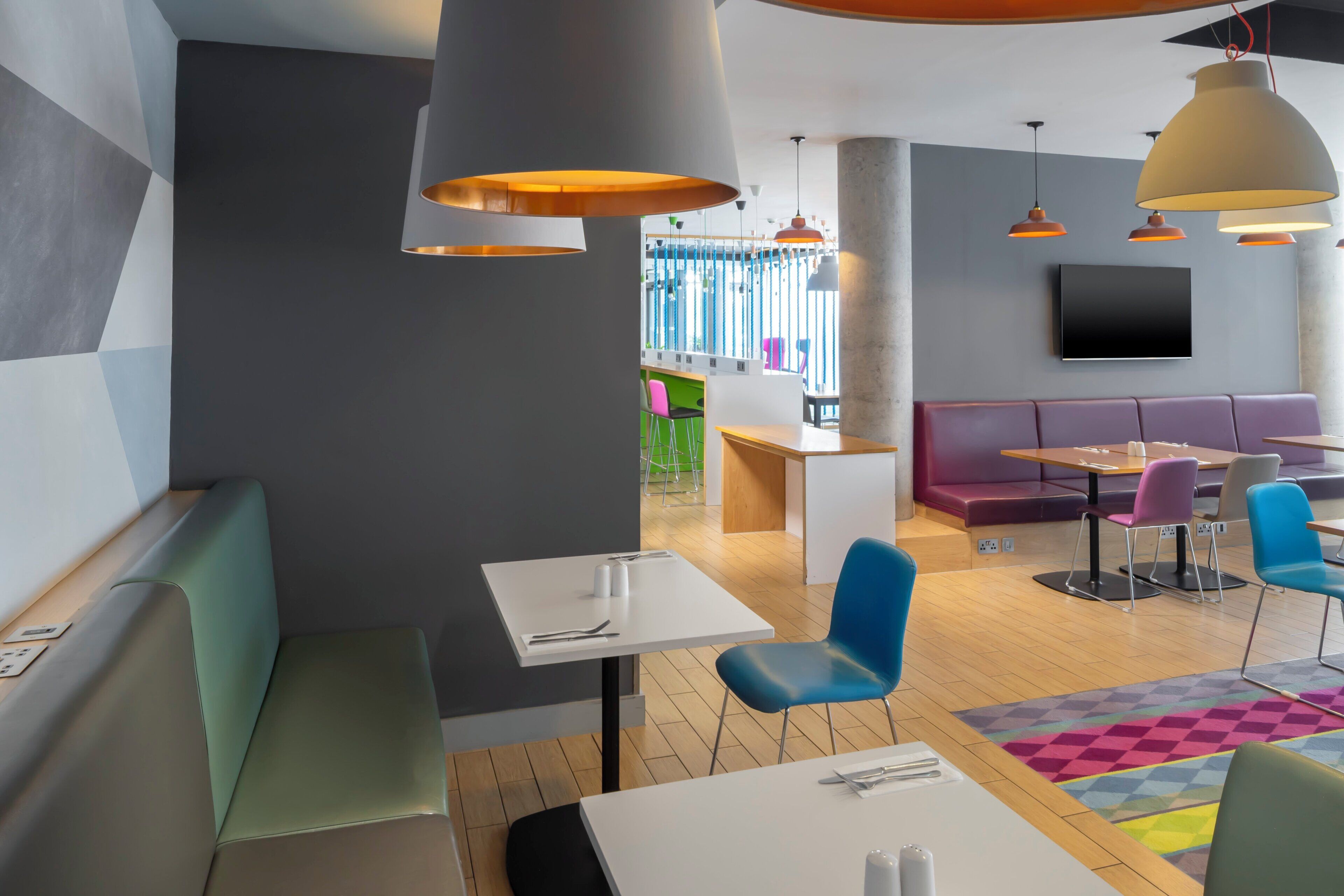 A modern interior with seating arrangements, tables, and pendant lighting.