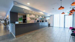 Un espace d’accueil moderne doté d’un comptoir, de sièges et d’une grande fenêtre.