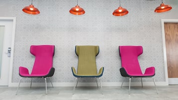 Three comfortable chairs line the wall, surrounded by a geometric pattern and pendant lights.