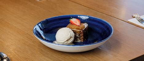 A dessert plate with ice cream and a piece of cake on a wooden table.