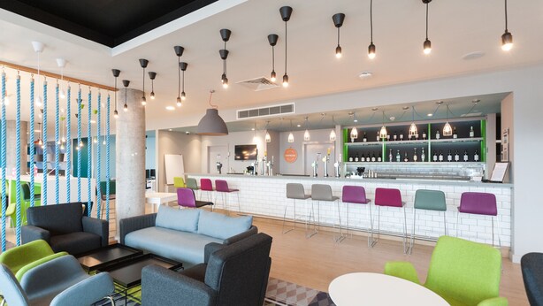 Un espace de détente moderne comprenant des canapés, des fauteuils, un bar et un coin café.