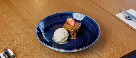 A dessert plate with a scoop of ice cream and a piece of cake on a wooden table.
