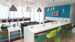Un espace bar moderne doté d’un long comptoir, de nombreux types de sièges et d’un éclairage suspendu.