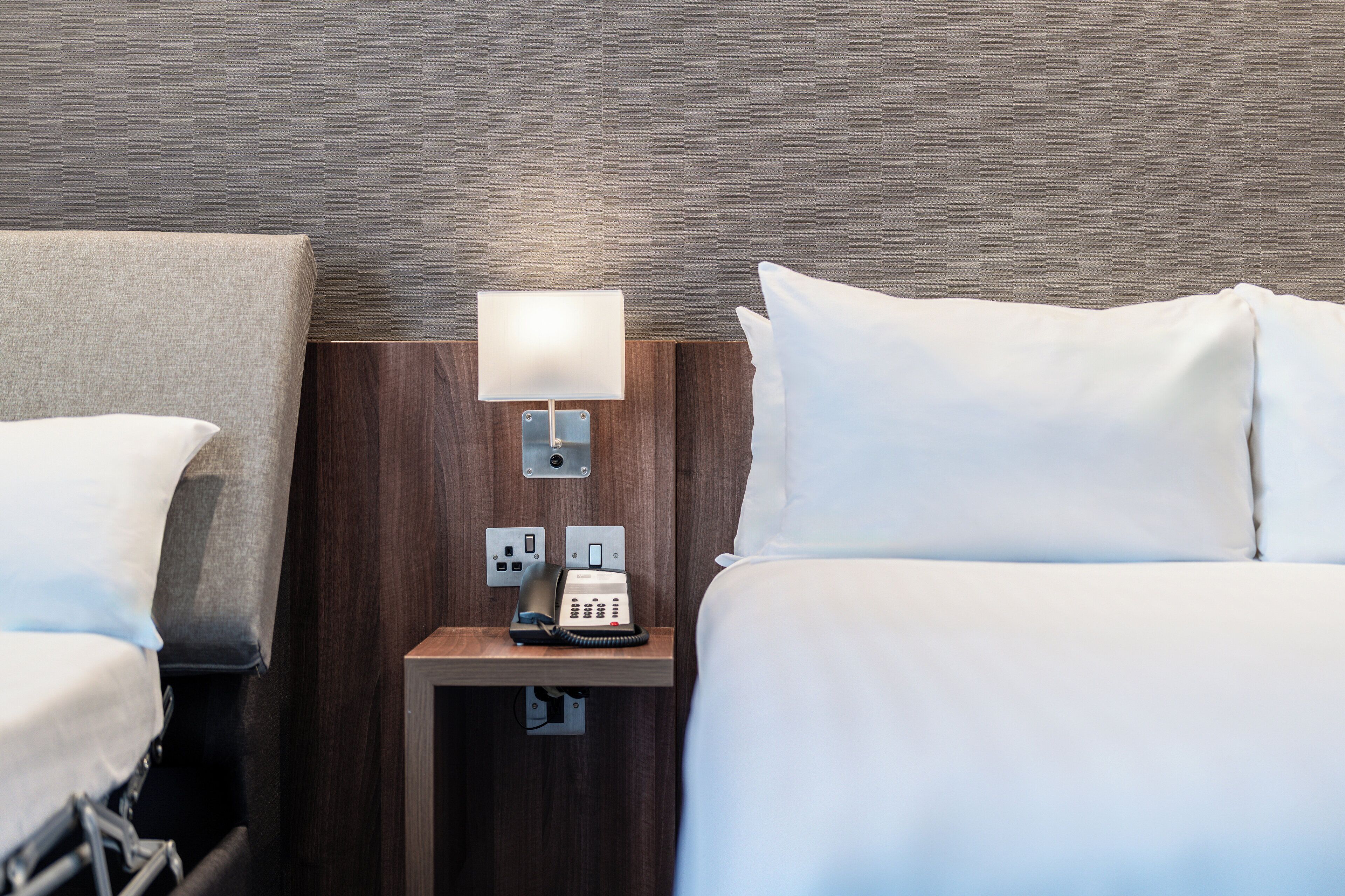 Une chambre d’hôtel avec un lit, une table de chevet avec une lampe et un téléphone.