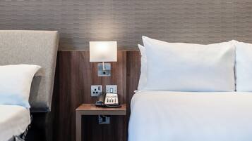 Une chambre d’hôtel avec un lit, une table de chevet avec une lampe et un téléphone.