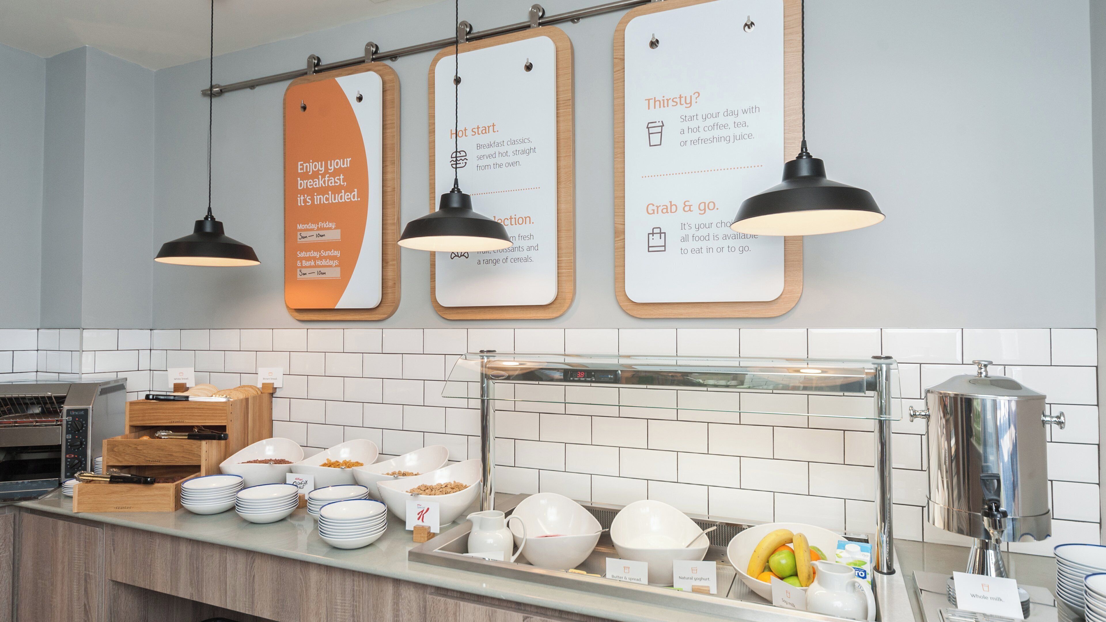 A breakfast buffet area with various food items and serving utensils.