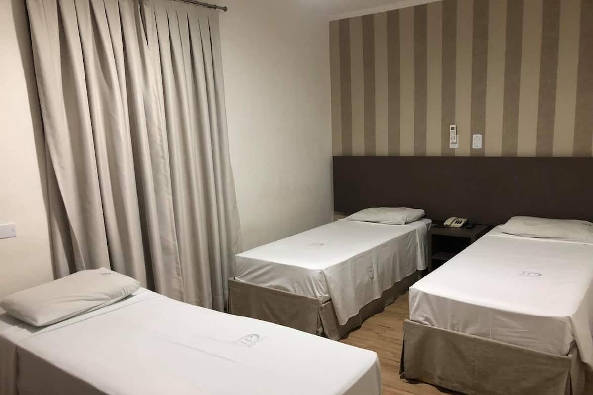 Ein Hotelzimmer mit zwei Einzelbetten, einer gestreiften Wand und einem Vorhang.