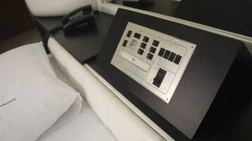 Une pièce avec un bureau noir, une chaise blanche, un coussin blanc et un téléphone noir.
