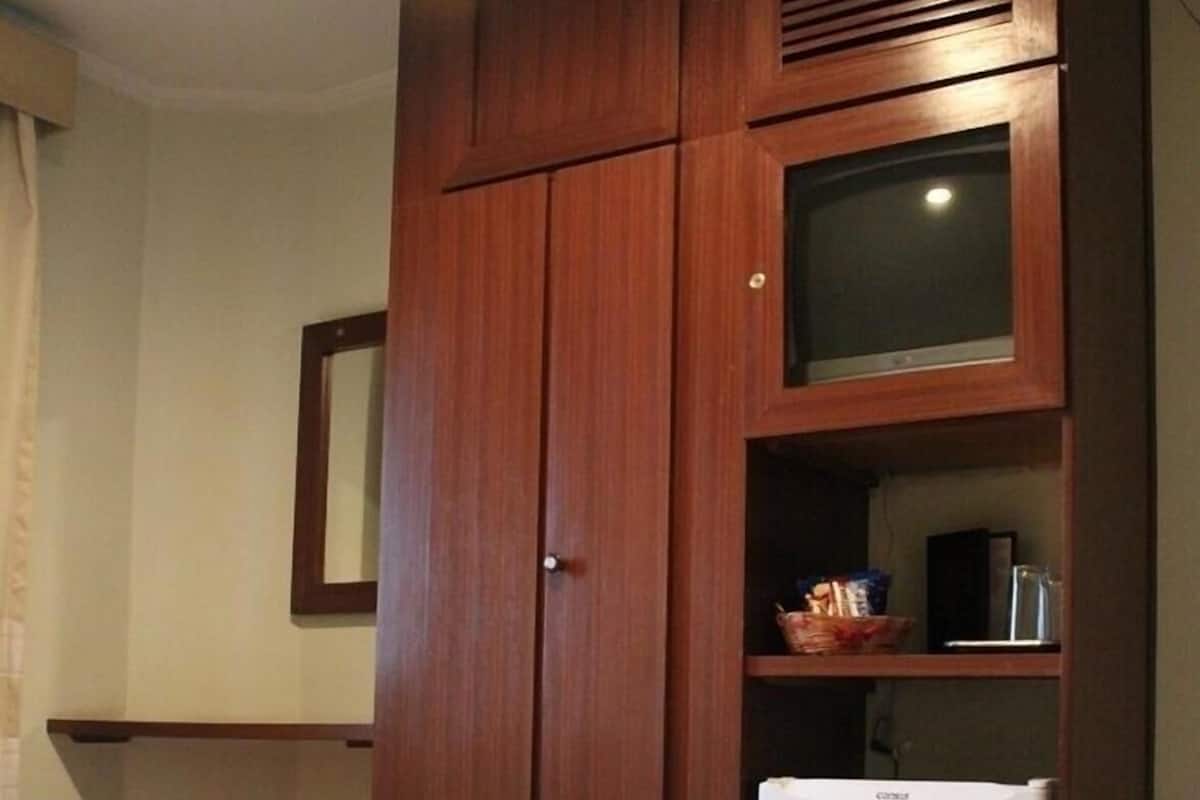 Ein Hotelzimmer mit einem Bett, einem Fernseher und einem kleinen Kühlschrank.