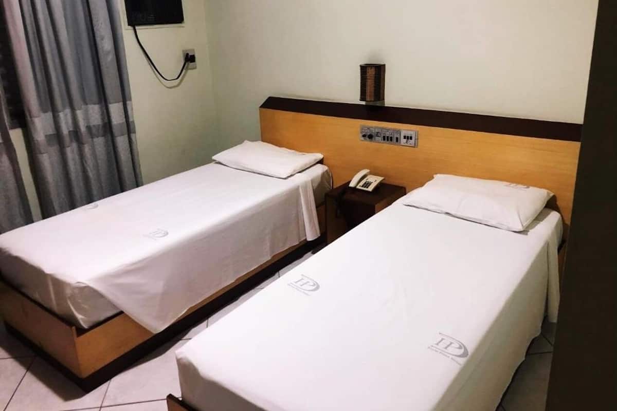 Ein Hotelzimmer mit zwei Einzelbetten, einem Nachttischtelefon und einer wandmontierten Klimaanlage.