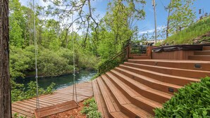 A wooden staircase leading to a viewing platform by a river, surrounded by lush greenery. - Stone Waters Inn (Bellaire)