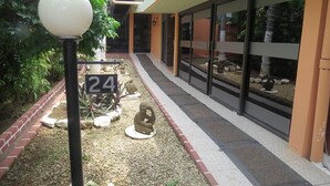 Un sendero con señales numeradas, un poste de luz y un edificio con grandes ventanales y un borde de ladrillo.