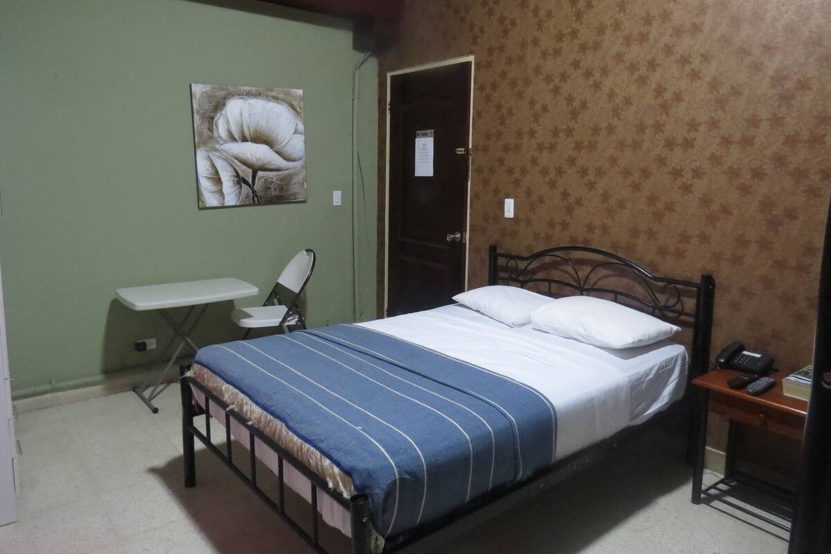 A bedroom with a single bed, a desk, and a chair.