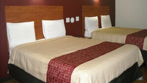 A hotel room with two beds, each with white pillows and beige bedding. - Bastrop Inn (Bastrop)