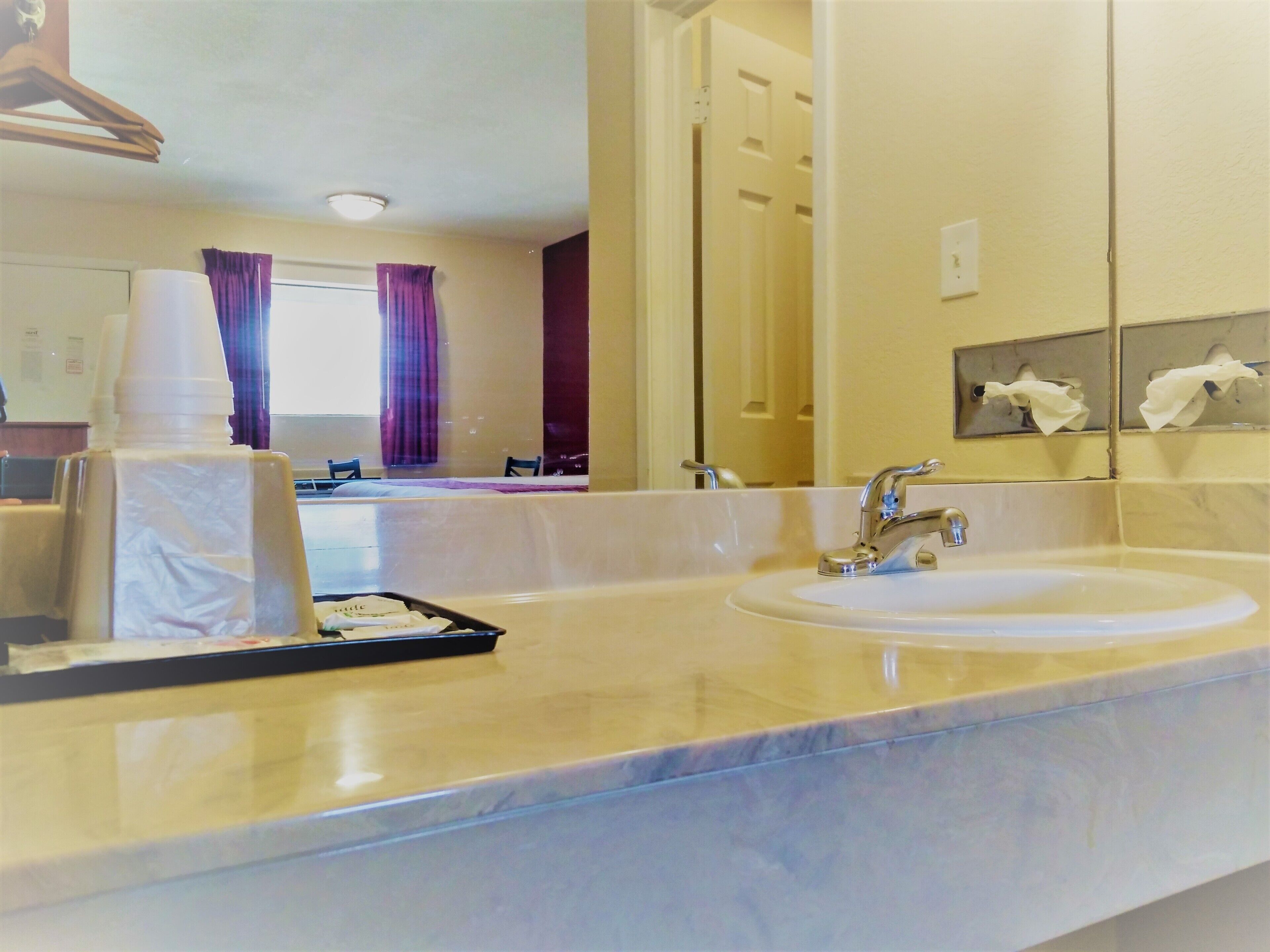 A hotel bathroom with a large mirror, two sinks, and a towel rack.