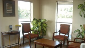 A room with a wooden table, two chairs, a potted plant, and a framed picture on the wall. - Bastrop Inn (Bastrop)