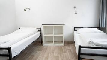 A room with two single beds, a white wardrobe, and a shower area.