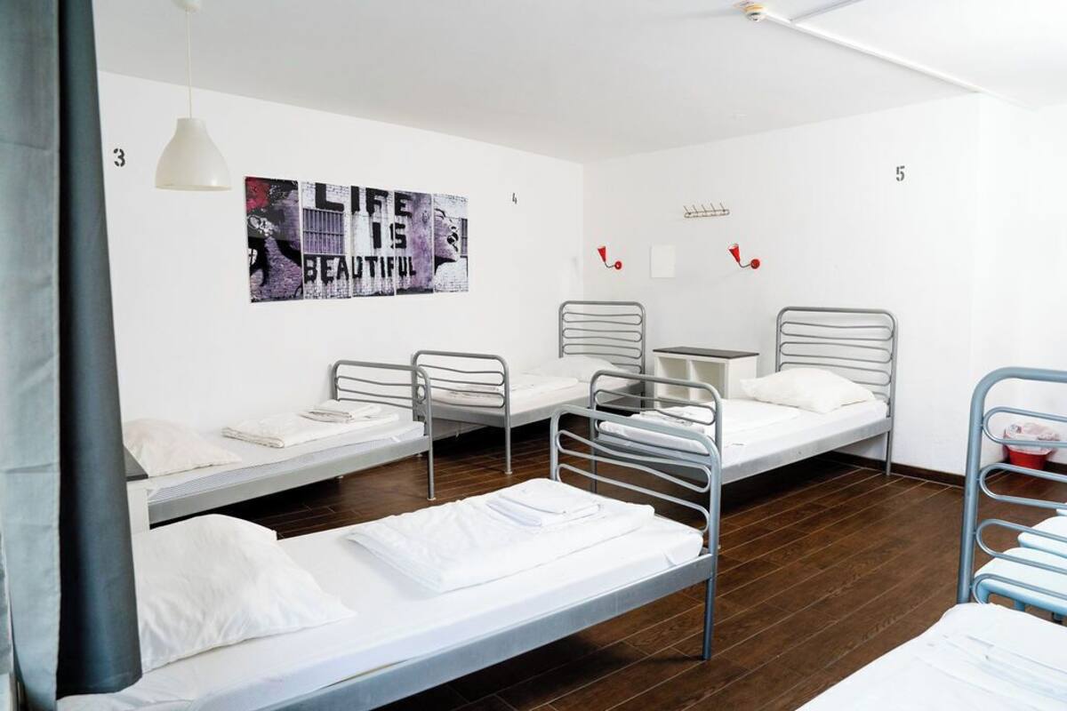 Ein Schlafsaalzimmer mit Etagenbetten, einem kleinen Tisch und einem an der Wand hängenden Kunstwerk.