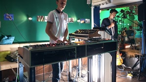 Una habitación con una pared verde, equipo de DJ y una guitarra.