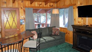 A wooden interior with a dining table, chairs, a sofa, a television, and a fireplace. - Edelweiss Lodge (Mammoth Lakes)