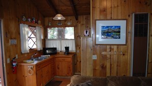 A wooden cabin interior with a kitchen, a sofa, and a framed picture on the wall. - Edelweiss Lodge (Mammoth Lakes)