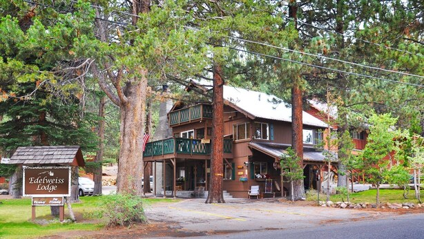 A lodge with a porch, a signboard, and a building with a red roof. - Edelweiss Lodge (Mammoth Lakes)