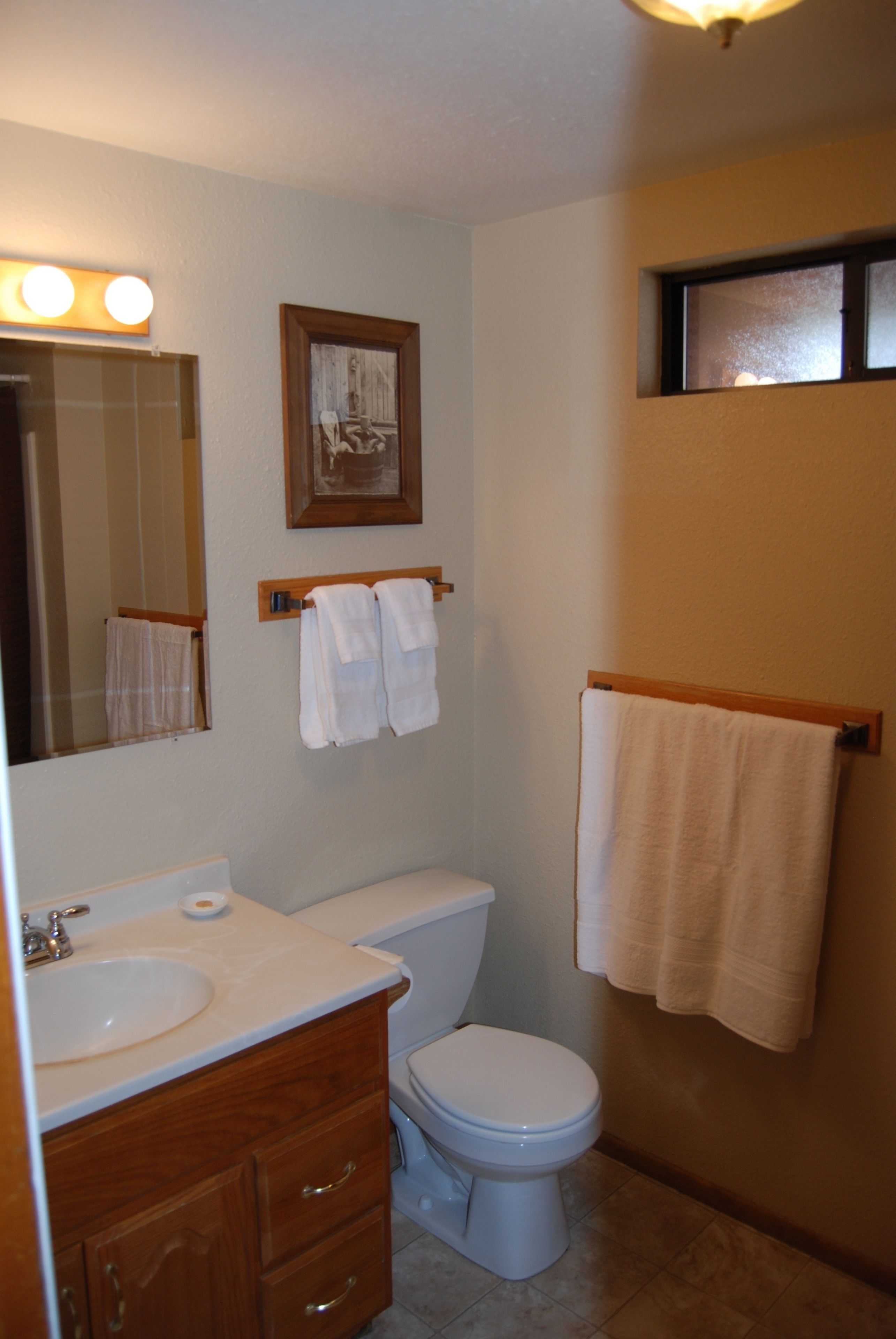 A bathroom with a sink, mirror, toilet, and towel rack.