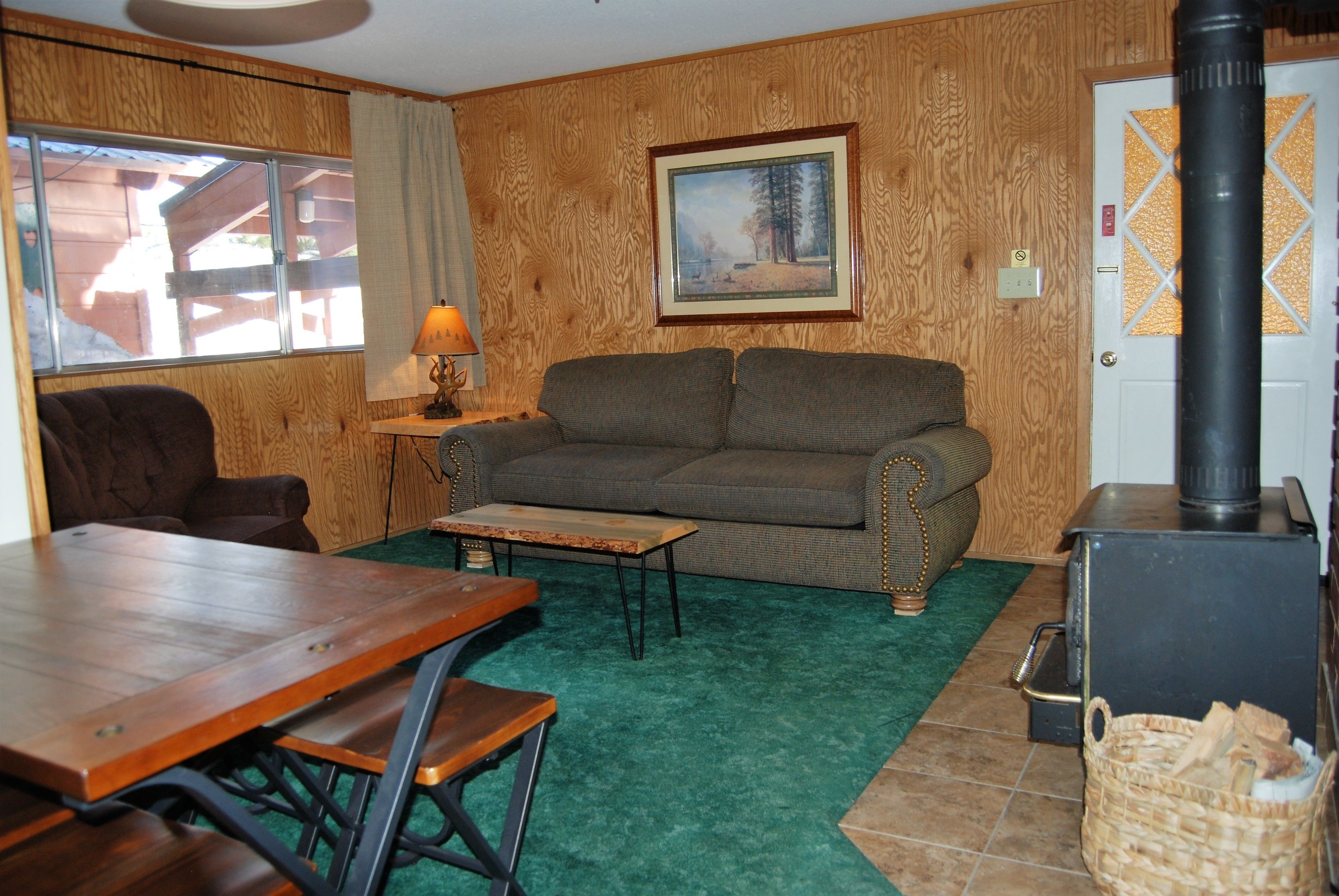 A cozy living room with a wooden wall, a sofa, a table, and a fireplace.