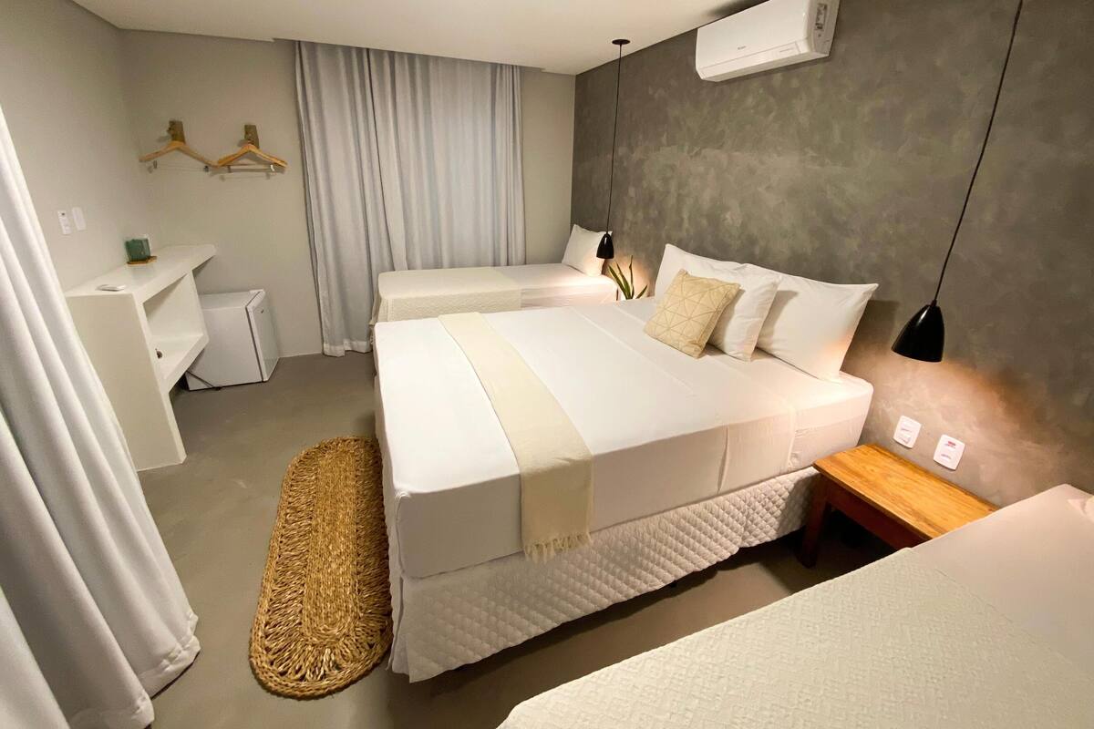 Ein modernes Hotelzimmer mit einem großen Bett, einem Nachttisch, einem kleinen Schreibtisch und einem Kleiderschrank.