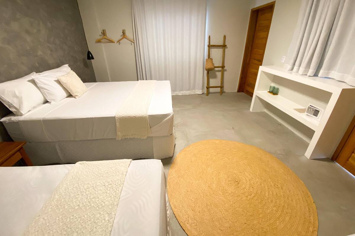 Ein Hotelzimmer mit zwei Betten, einem kleinen runden Tisch, einer Holzleiter und einem weißen Regal mit einem Radio.