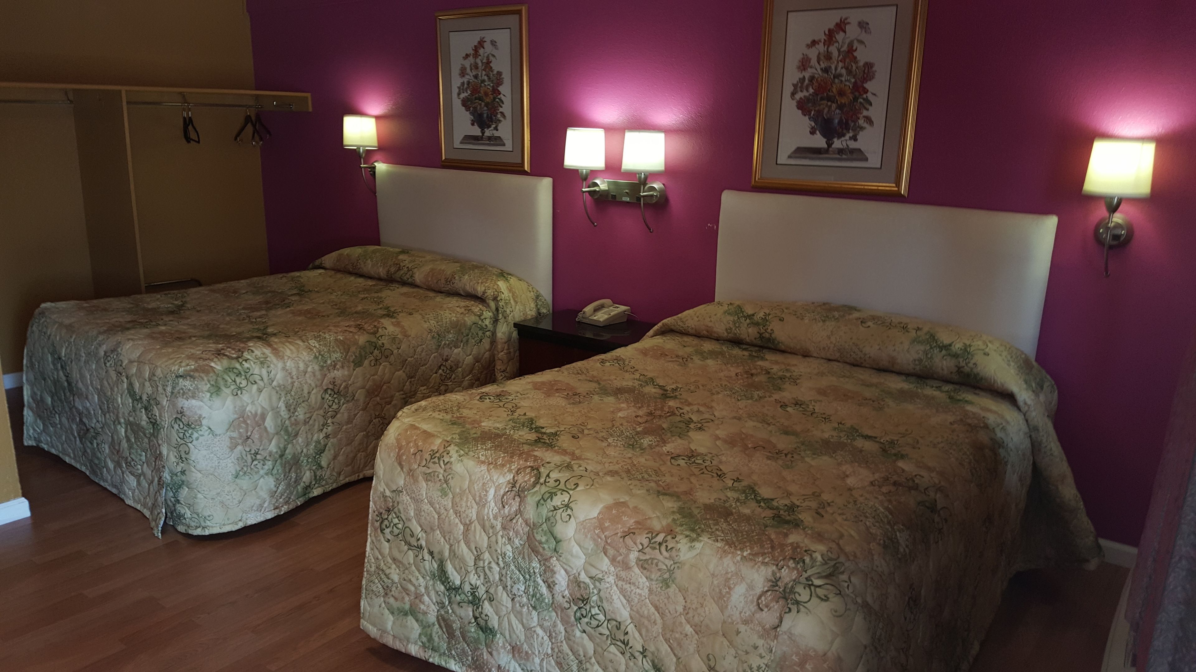A hotel room with two beds, purple walls, and a wooden floor.