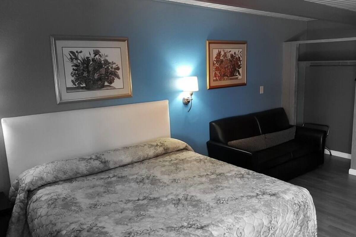 Un dormitorio con cama, sofá y dos cuadros en la pared.