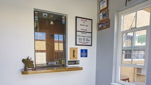 A hotel reception area with a reception desk, a window with a view, and various signs and decorations on the walls. - Budget Inn Vallejo/Napa Valley (Vallejo)