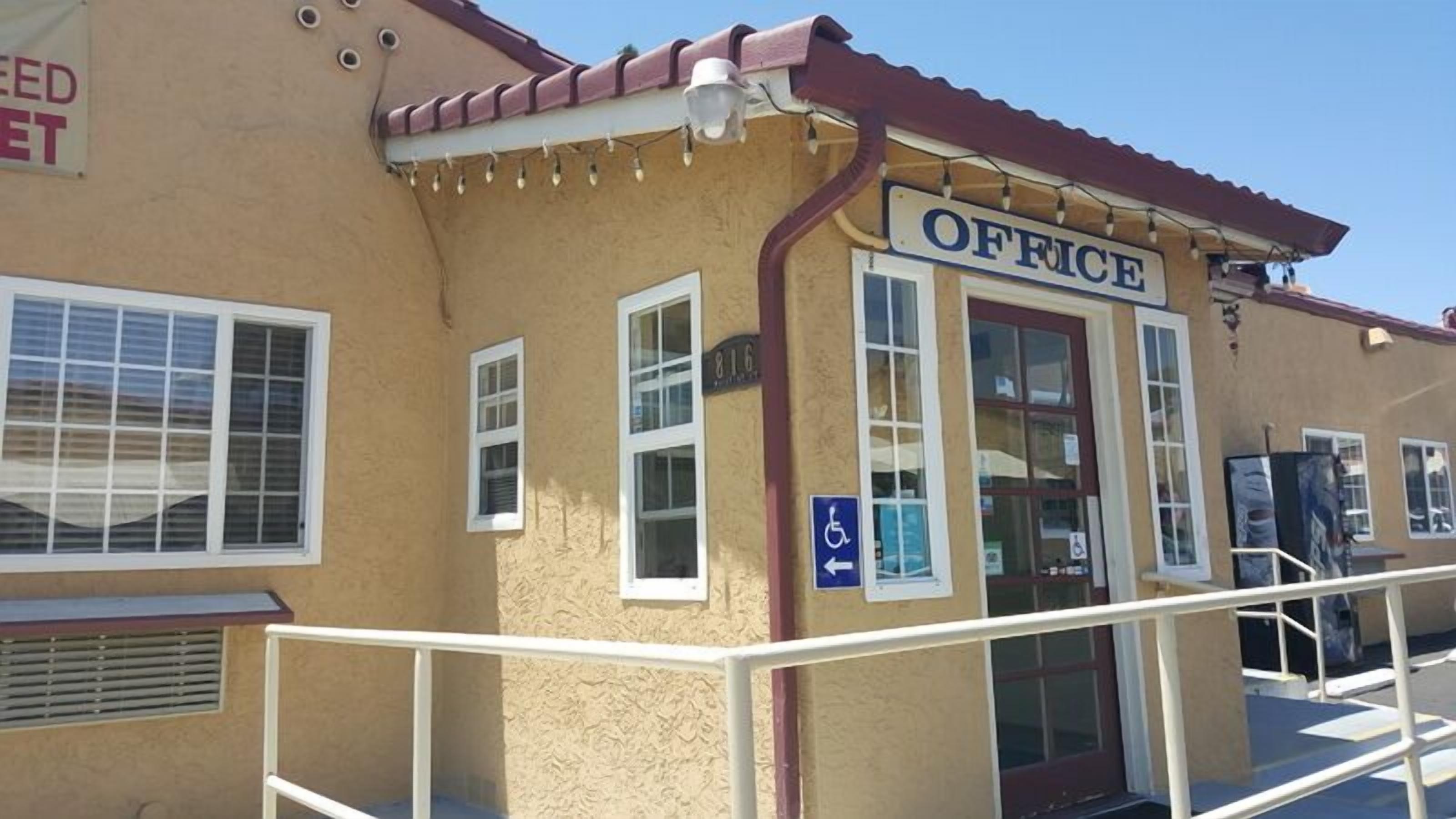A building with an 'OFFICE' sign, a wheelchair accessibility sign, and a number '816' on the wall.