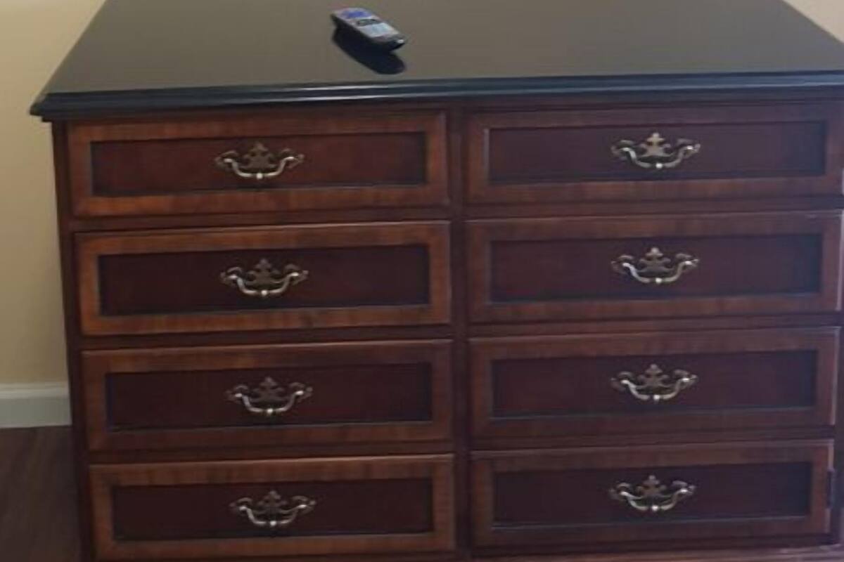 Un aparador de madera con varios cajones y un televisor de pantalla plana montado en la pared de arriba.