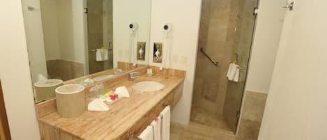 A bathroom with a wooden vanity, a large mirror, a shower, and a towel rack.