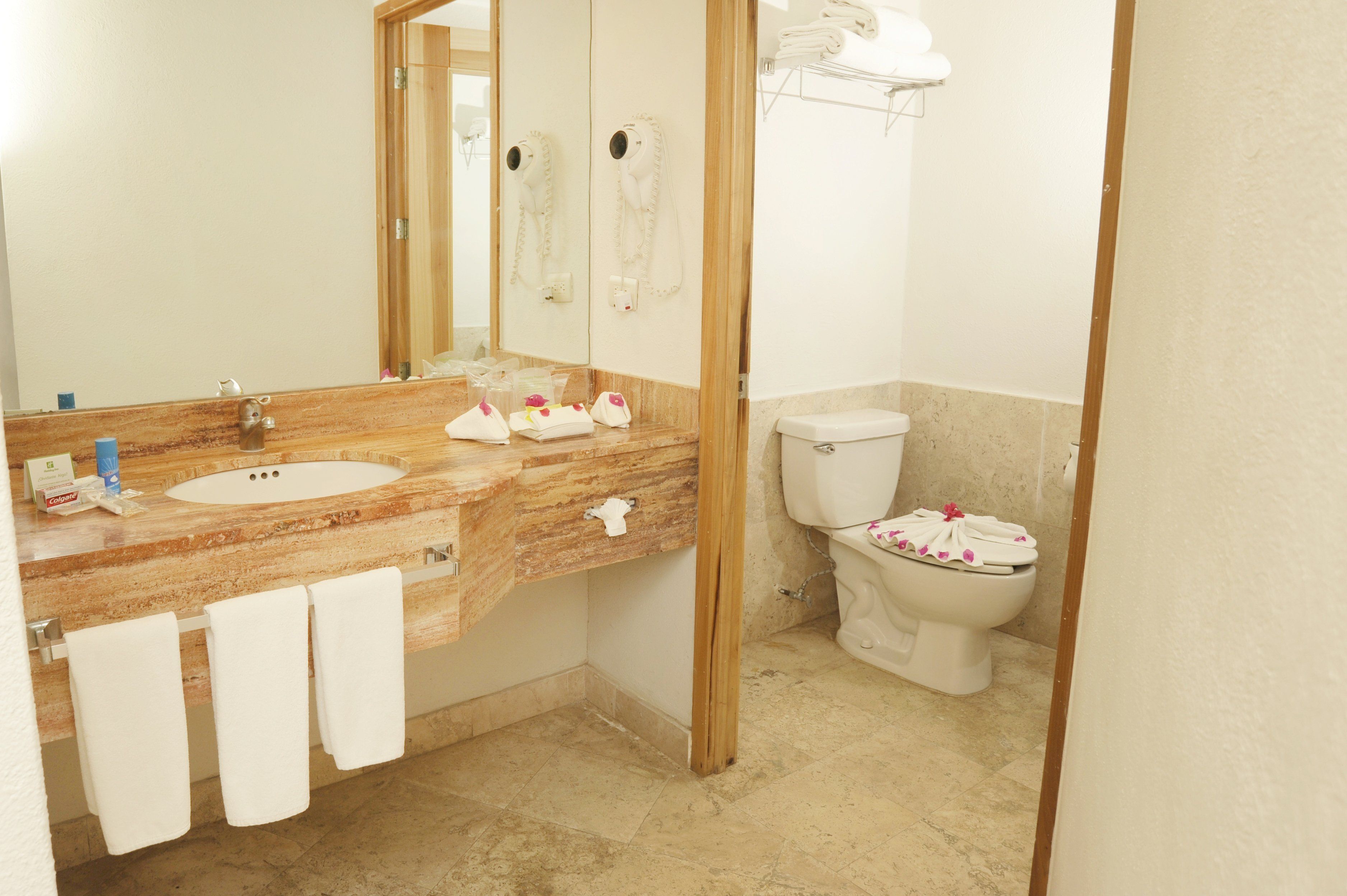 A bathroom with a marble sink, a toilet, and a mirror.
