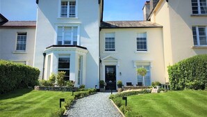 A two-story building with a symmetrical facade, a central entrance with a black door, and a gravel pathway leading to the entrance. - Tavistock House Hotel (Tavistock)