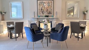 A modern living room with a fireplace, a large abstract painting, and a seating arrangement of blue upholstered chairs. - Tavistock House Hotel (Tavistock)