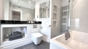A modern bathroom with a bathtub, toilet, and vanity. - Tavistock House Hotel (Tavistock)