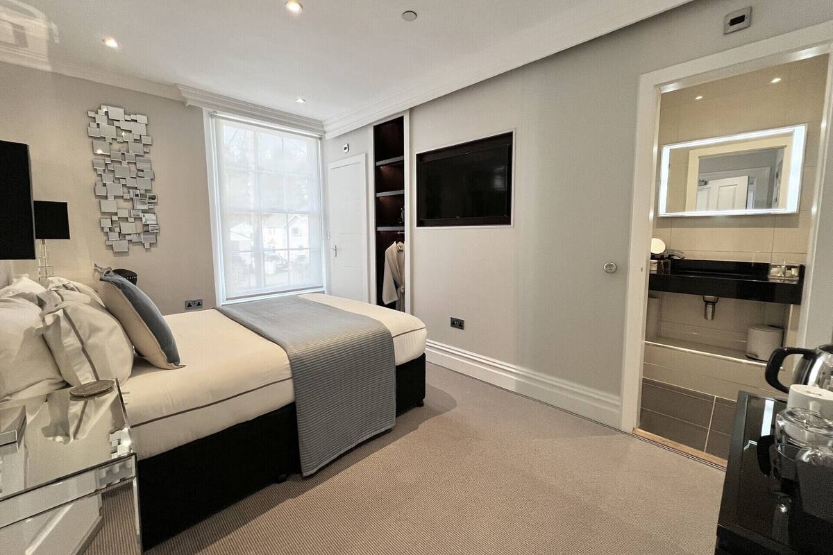 A modern bedroom with a bed, a bedside table, a mirror, a wardrobe, and a TV.