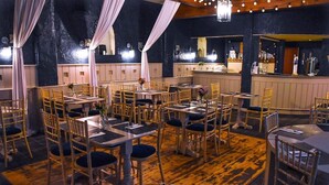 A restaurant with multiple tables and chairs, a bar area, and a wooden floor. - Dobbins Inn (Carrickfergus)
