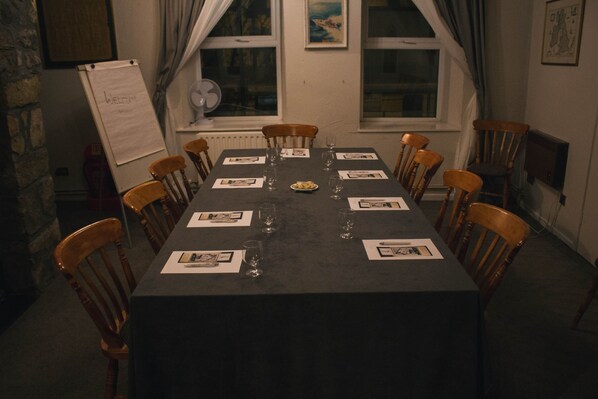 A conference room with a long table, wooden chairs, and a whiteboard.