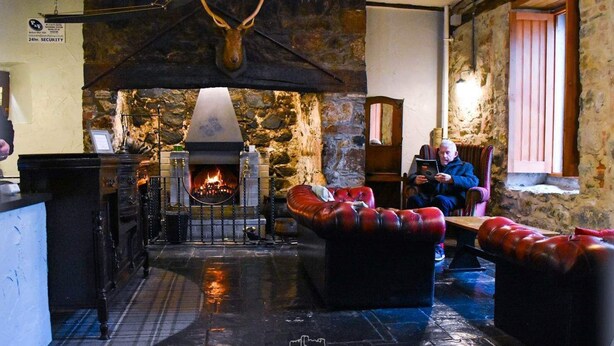 A cozy interior with a stone fireplace, leather sofas, and a rustic stone wall. - Dobbins Inn (Carrickfergus)