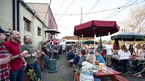 An outdoor patio area with wooden tables and benches, surrounded by umbrellas. - McMenamins Olympic Club (Centralia)