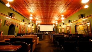 A theater with rows of seats, a large screen, and ornate ceiling details. - McMenamins Olympic Club (Centralia)