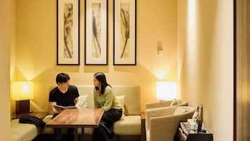 Une chambre d’hôtel avec un canapé, une petite table en bois et trois tableaux abstraits encadrés accrochés au mur.