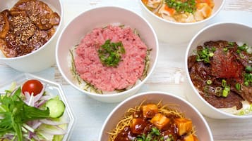 A variety of bowls containing different dishes, including rice, noodles, and meat, arranged on a table.